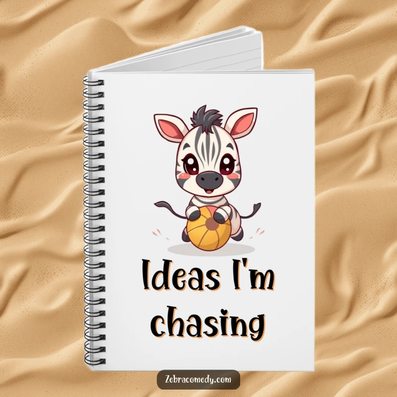 Funny zebra character with wide, excited eyes chasing a bouncy ball on the cover of a notebook for playful notes.